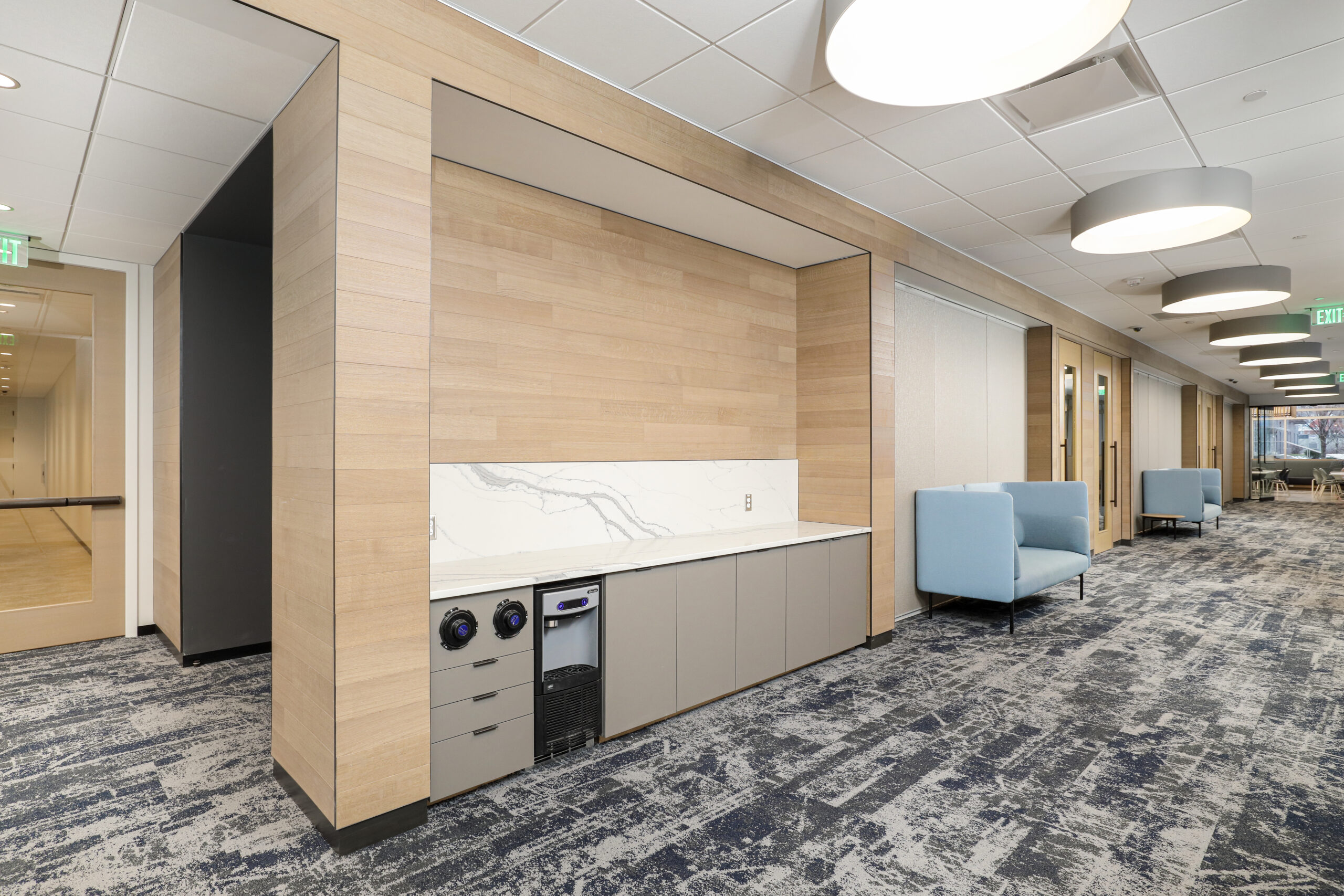 An open-plan office space featuring rows of grey cubicles, a polished concrete floor, and exposed ceiling ductwork.