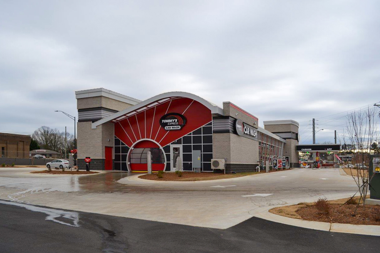 Tommy’s Express Car Wash building with a curved roof, red and black accents, and a cashier station.