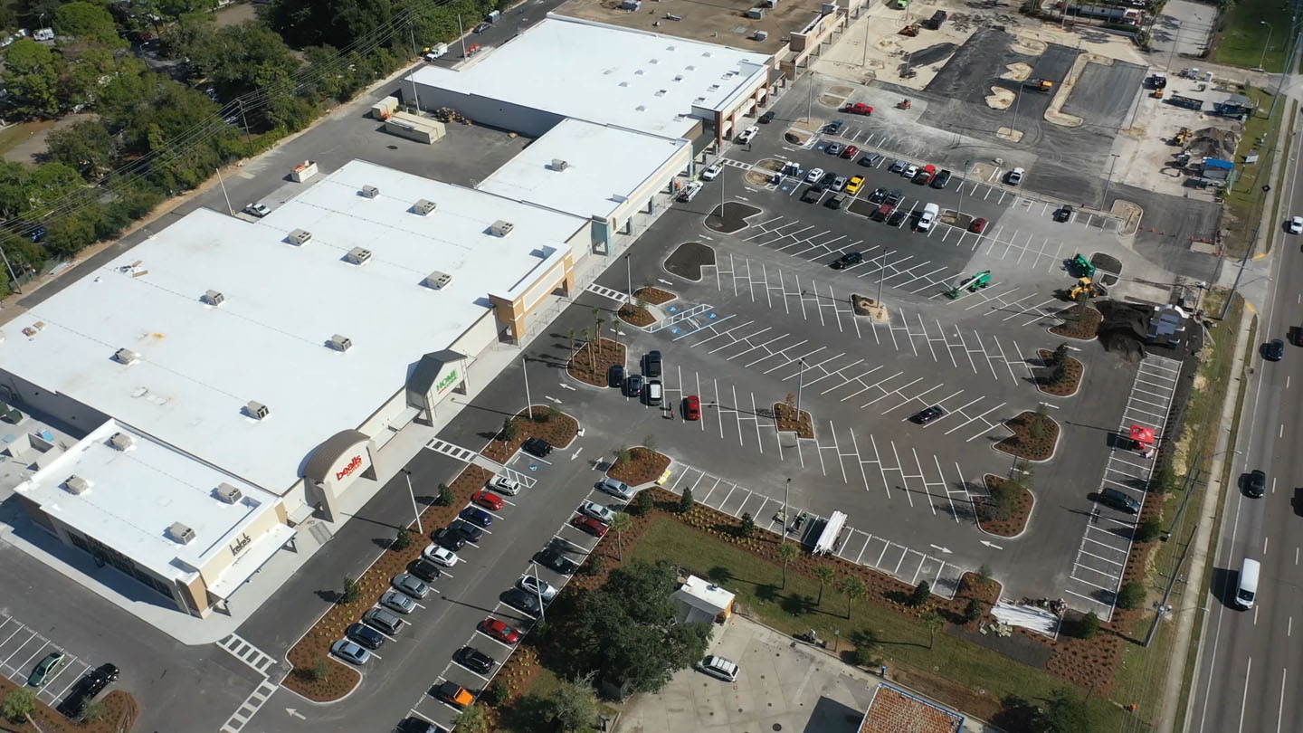Aerial view of a shopping center with a large parking lot and a construction area.
