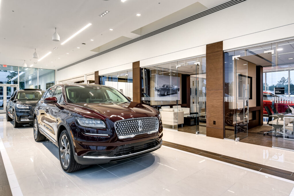 A dark red Lincoln SUV on display in a brightly lit car dealership showroom.
