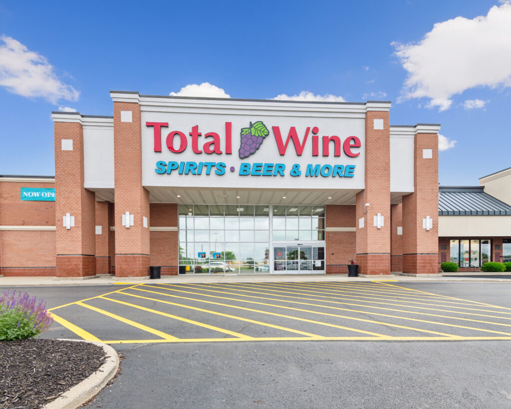 The exterior entrance of a Total Wine & More store with a brick facade and a large parking lot.