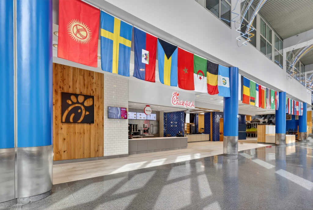 A Chick-fil-A restaurant interior with a row of international flags hanging from the ceiling above the service counter.