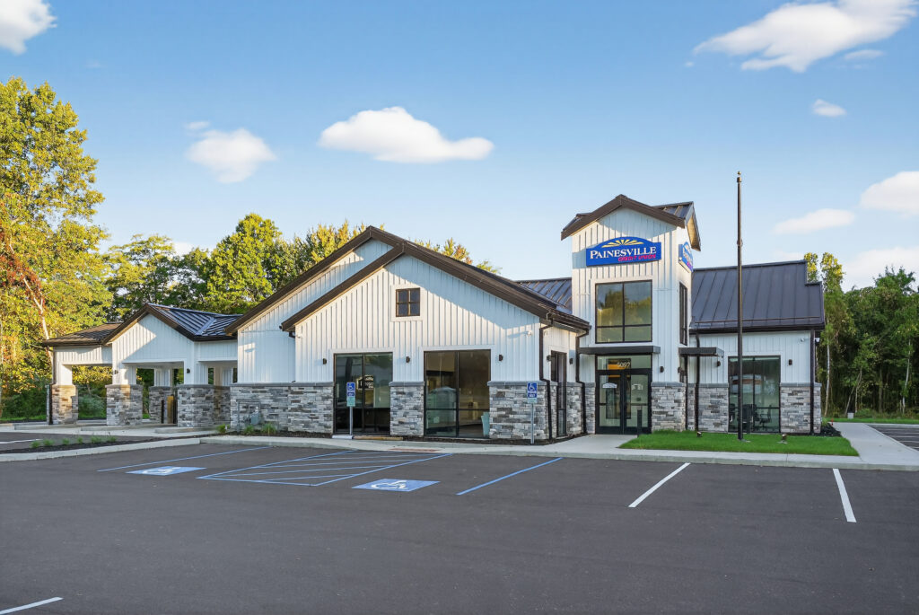Painesville Dental Group office building with white siding, stone base, and a parking lot.