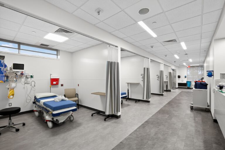 A row of hospital exam bays with rolling beds and medical equipment.