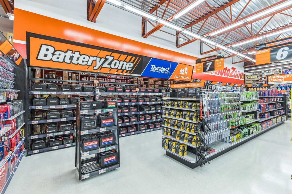 AutoZone store aisle featuring a Battery Zone section with various car batteries on display racks.