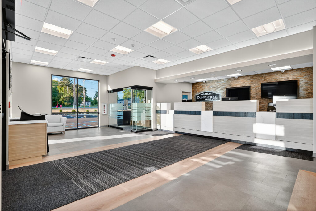 The interior of a Painesville Credit Union branch featuring a service counter, a glass-walled office, and a waiting area.