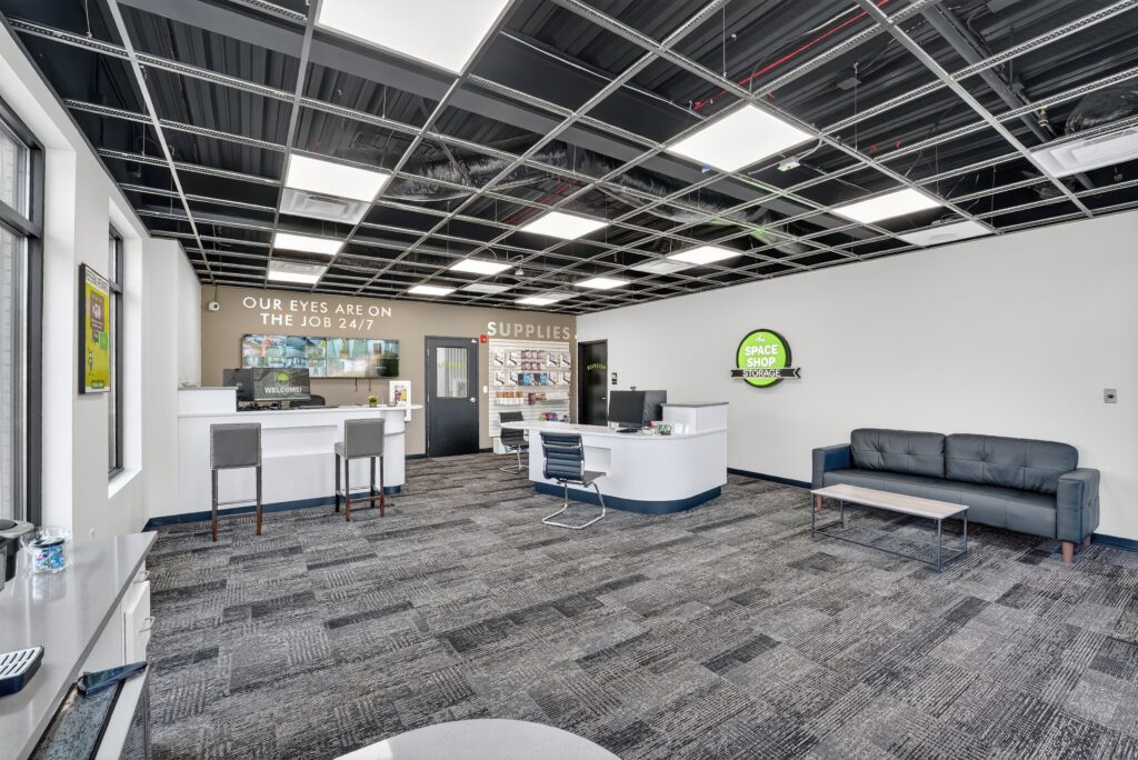 Interior view of a Space Shop Storage leasing office with a reception desk, waiting area, and display of packing supplies.