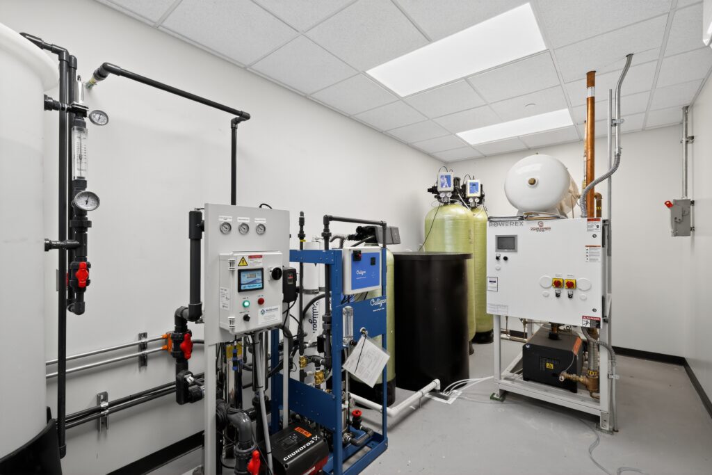 Industrial water treatment system with filtration tanks, pumps, and control panels in a utility room.