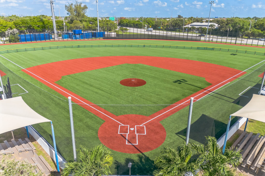 High-angle view of an empty baseball field with red dirt paths and home plate in the foreground.