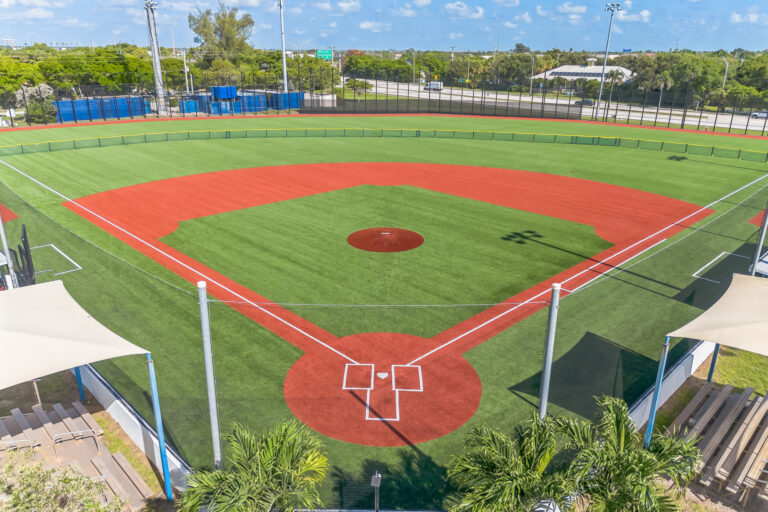 High-angle view of an empty baseball field with red dirt paths and home plate in the foreground.