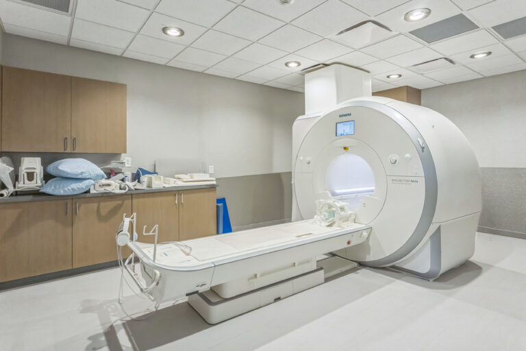 An MRI scanner in a medical imaging room with a patient bed extended in front of the machine.