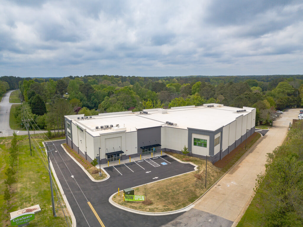 Aerial view of an Extra Space Storage facility with a parking lot and “Now Open” signs.