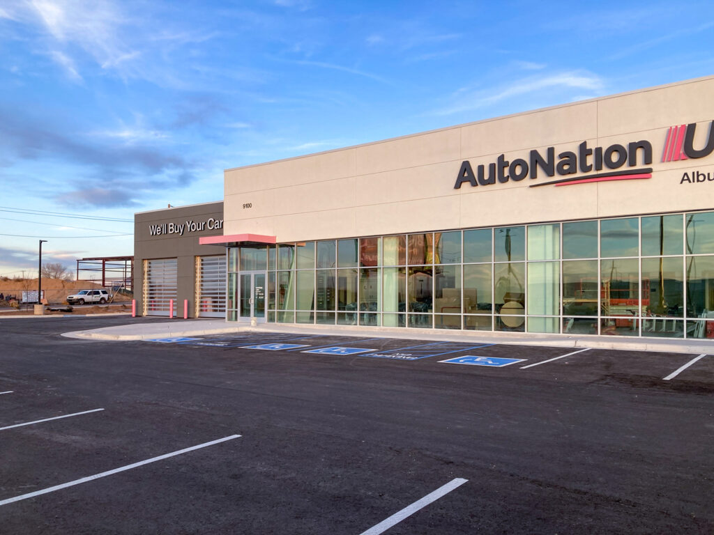 AutoNation dealership building with a “We’ll Buy Your Car” service entrance and a large parking lot.