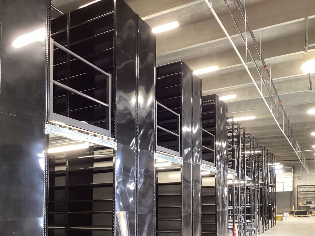 Rows of tall, black metal industrial shelving units in a warehouse.