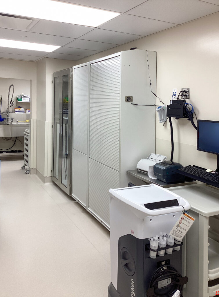 A hospital workstation with medical storage cabinets, a computer, and a mobile equipment cart.