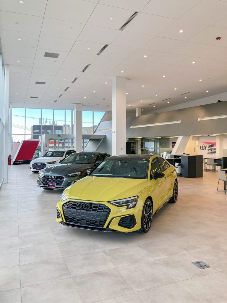 Three Audi sedans parked in a bright, modern car dealership showroom.