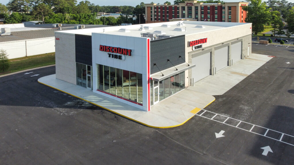Aerial view of a Discount Tire store with a corner storefront and three service bay doors.