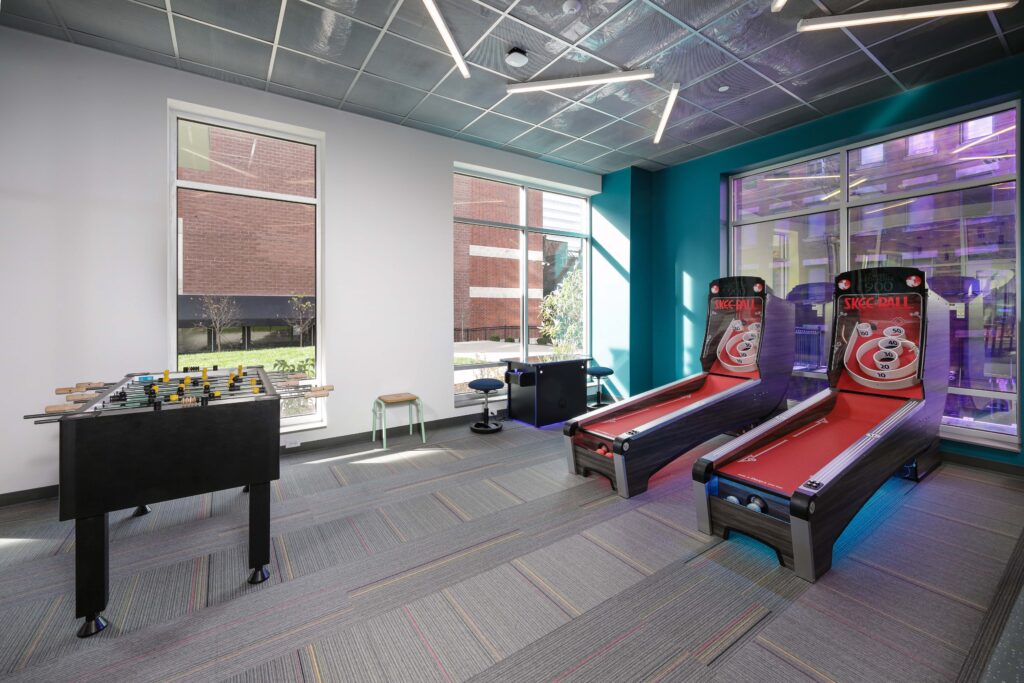 Game room with a foosball table, two Skee-Ball machines, a small table, and stools.