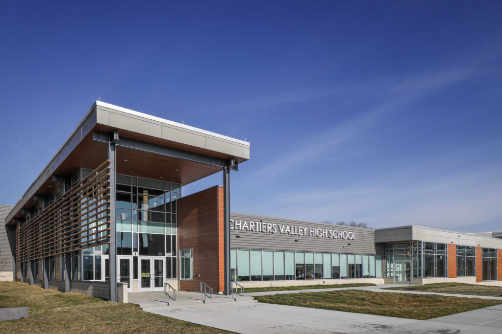 Exterior of Chartiers Valley High School with a large glass entrance, metal siding, and a clear blue sky.
