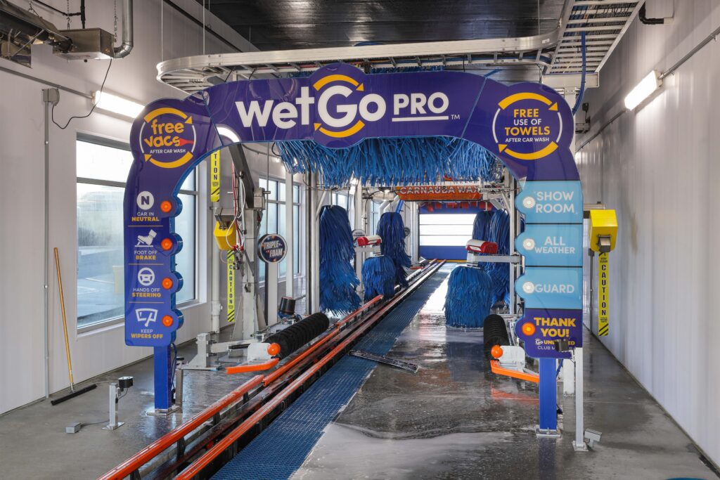 The entry arch of a wetGo PRO car wash tunnel featuring instructional signage for drivers and equipment details.