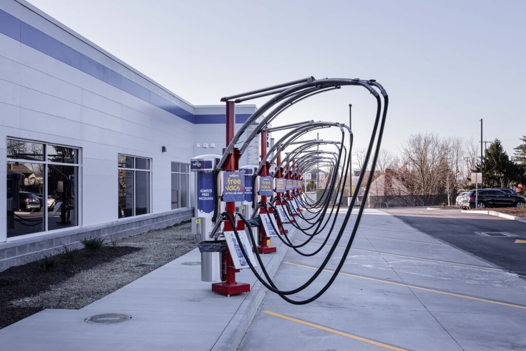 A row of car vacuum stations with overhead hoses located next to a modern building.