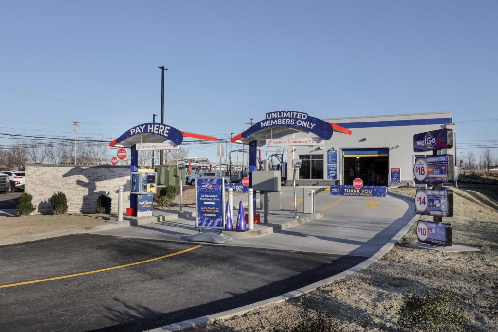 Two car wash entrance lanes labeled “Pay Here” and “Unlimited Members Only” leading to a wash bay.