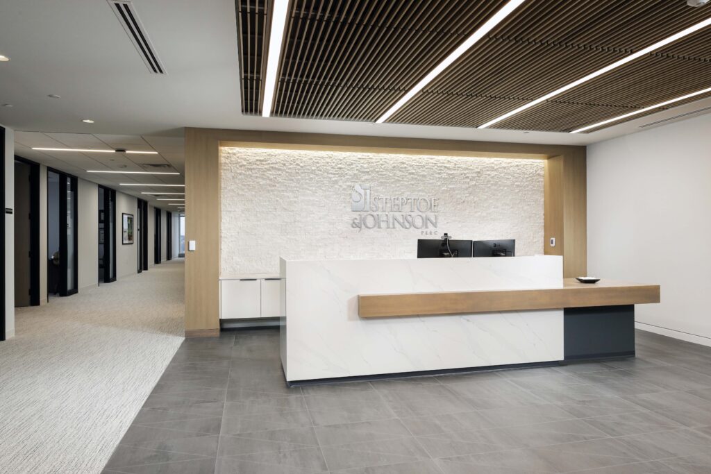 Reception desk with the Steptoe & Johnson PLLC logo on a textured stone wall in an office lobby.