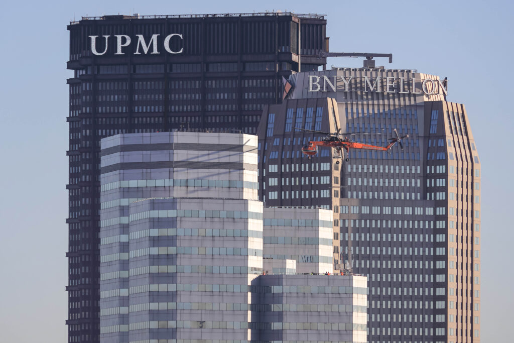 An orange helicopter flies between the UPMC and BNY Mellon skyscrapers in Pittsburgh.