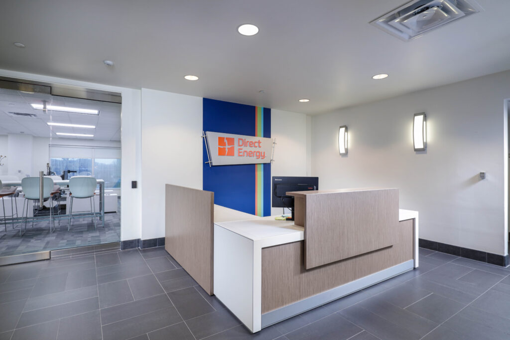 Reception desk in a modern office with a Direct Energy logo on the wall behind it.