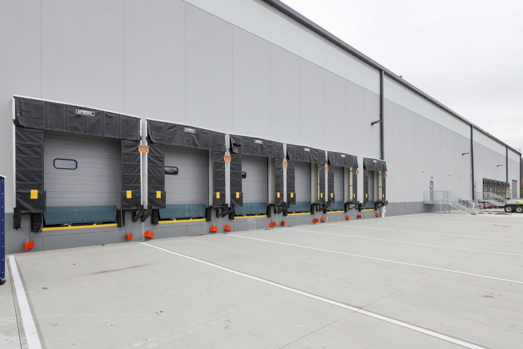 A row of warehouse loading dock bays with gray doors and black dock shelters.