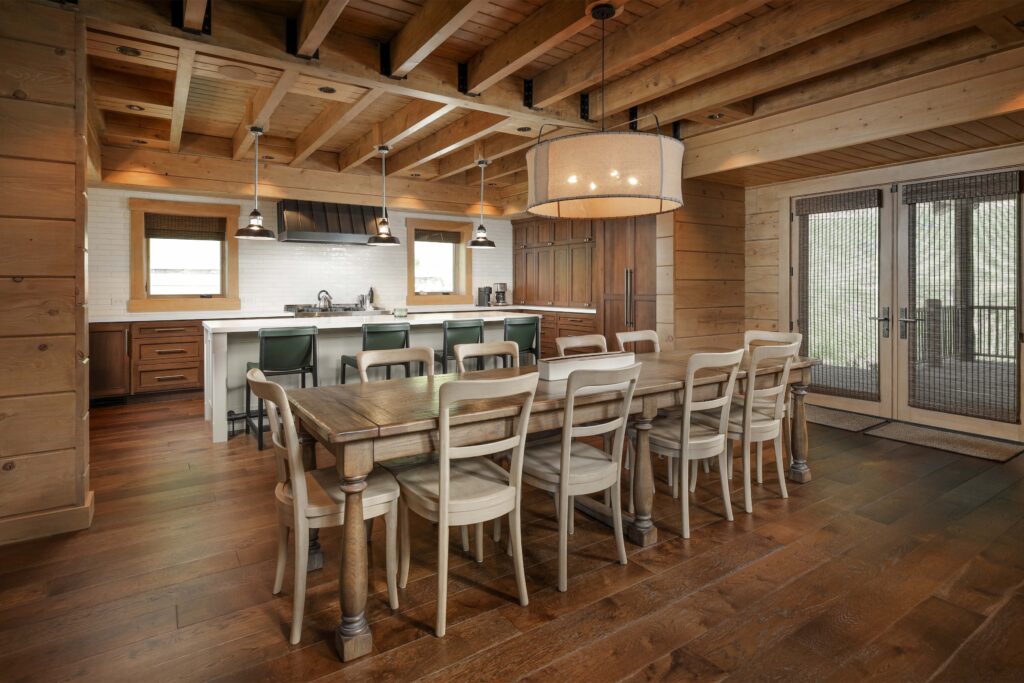 A rustic kitchen and dining area with a long wooden table, chairs, and a kitchen island with bar stools.