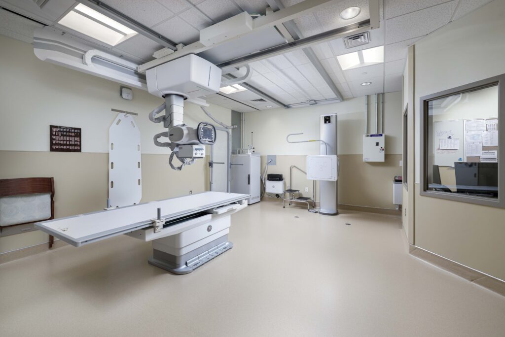 An X-ray examination room featuring an adjustable imaging table and an overhead X-ray tube.