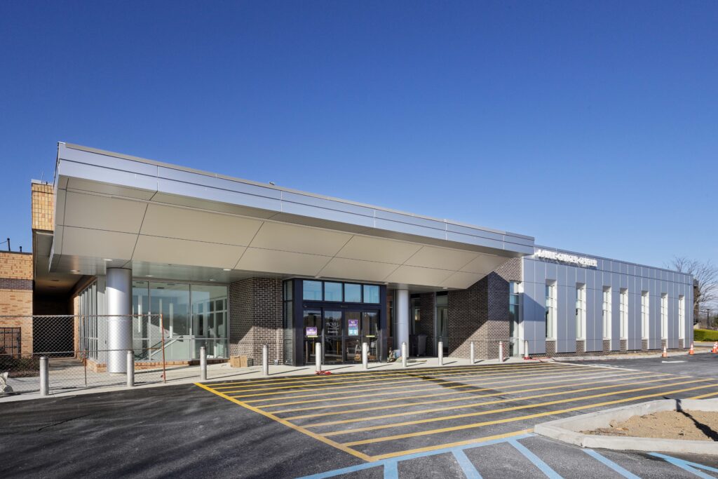 Exterior of a single-story commercial building with a large metal overhang above the glass entrance doors.
