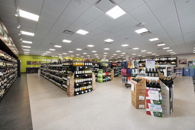 Interior view of a spacious liquor store with rows of wine and spirits arranged on shelves and cardboard displays.