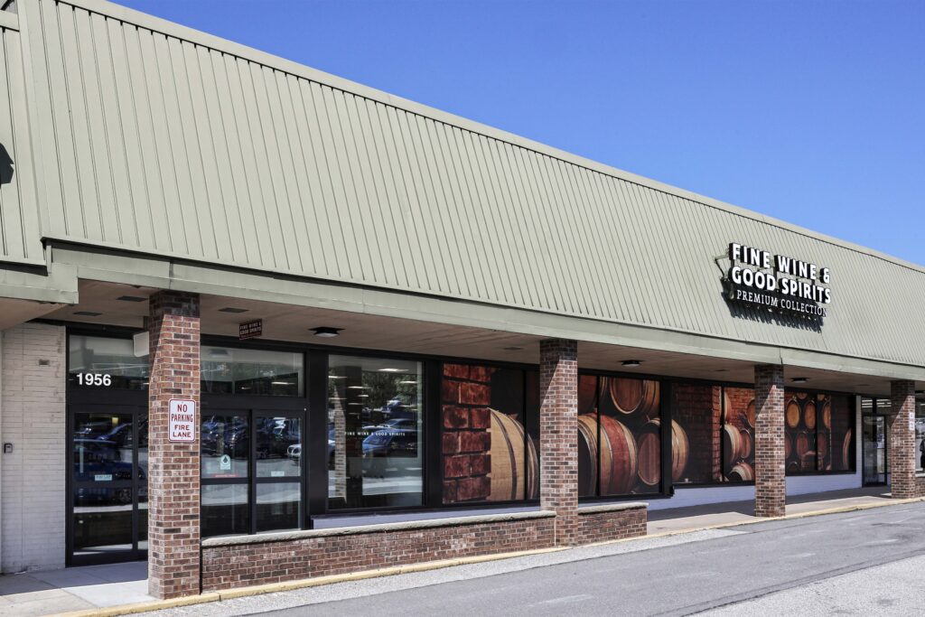 Exterior of a Fine Wine & Good Spirits store with large glass windows featuring images of wine barrels.