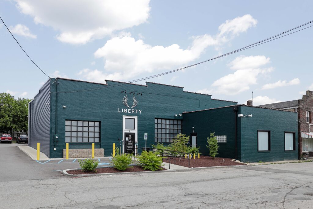 A dark green, single-story brick building with the word “LIBERTY” and a wing logo centered above the glass front entrance.