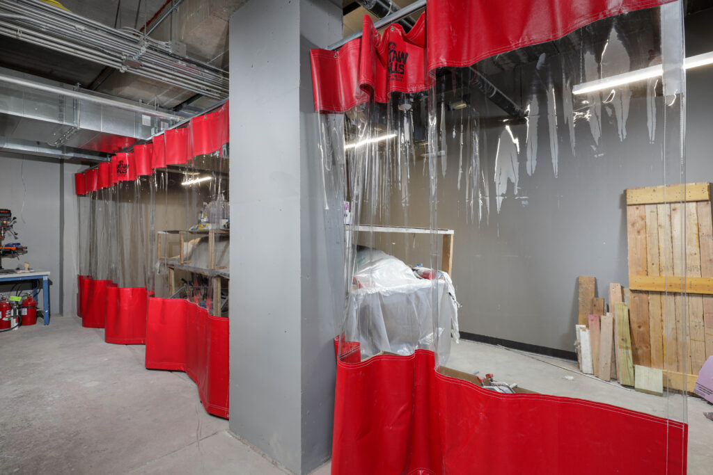 Red welding curtains sectioning off a workspace in an industrial room.
