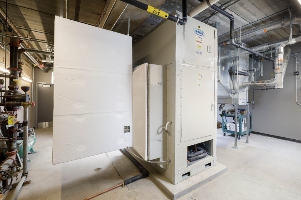 Large industrial HVAC unit in a utility room with a white insulated panel partially open.
