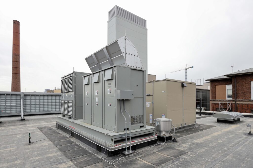 Industrial HVAC equipment and a tall exhaust stack on a building rooftop.
