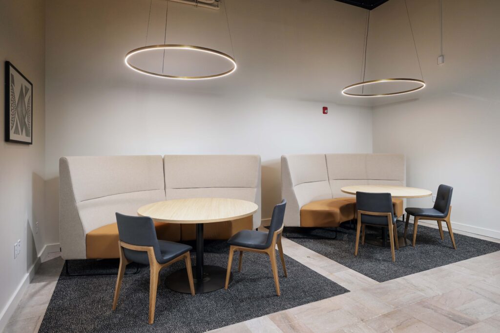 Two curved seating booths with round tables and chairs in a modern office space.