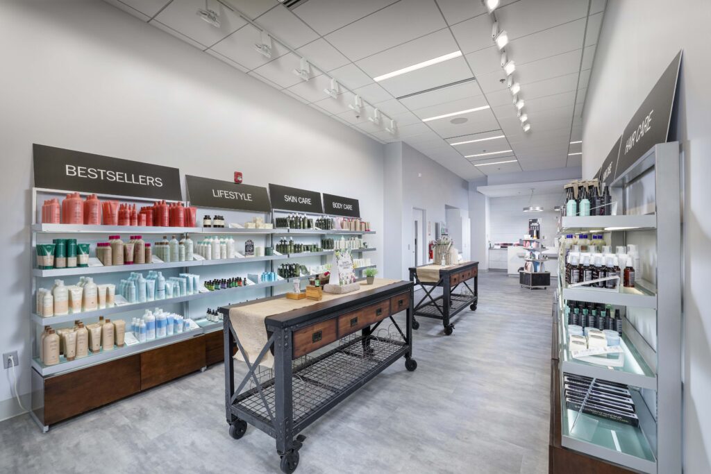 Interior of a beauty supply store with shelves organized by category, including bestsellers, lifestyle, skincare, and body care, with display tables in the center.