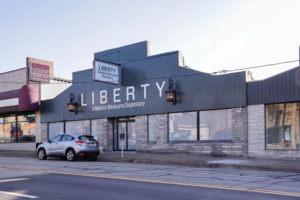 Exterior of the Liberty Medical Marijuana Dispensary building with a silver SUV parked in front.