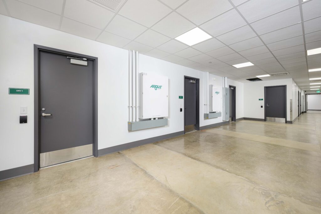 A long hallway with grey doors and two Argus wall-mounted electrical units.