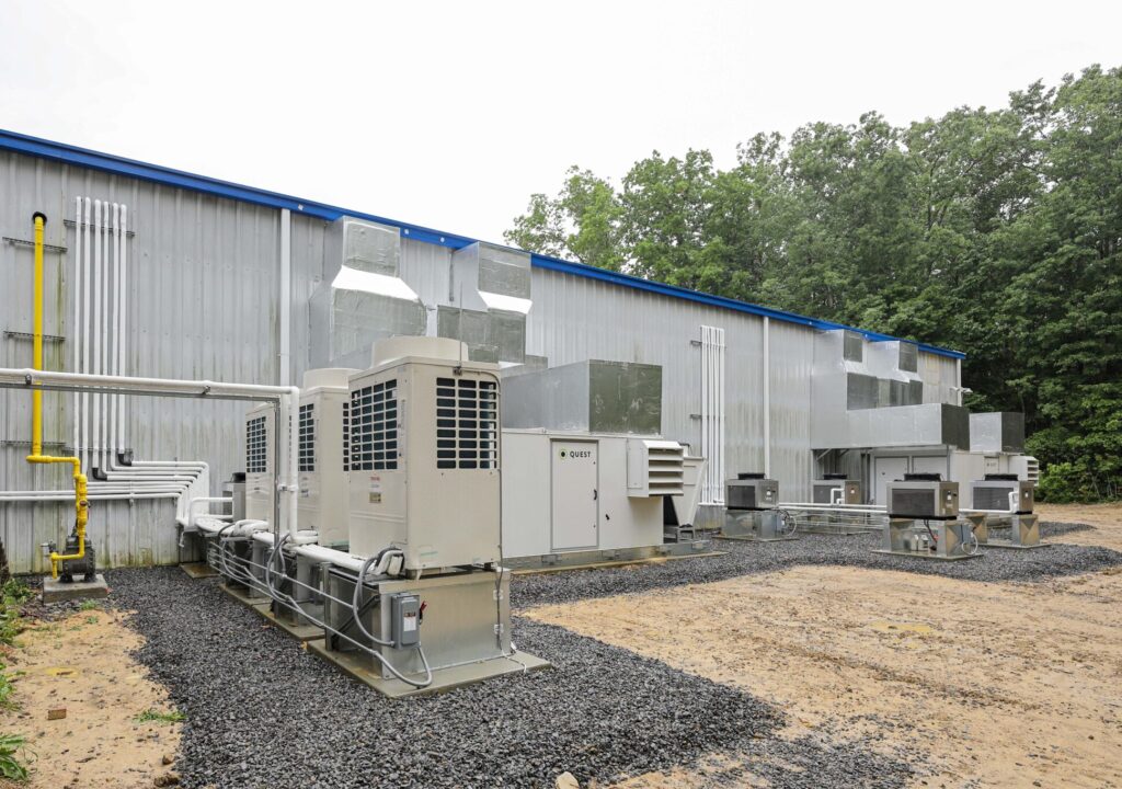 Industrial HVAC units and ductwork positioned outside a corrugated metal building.