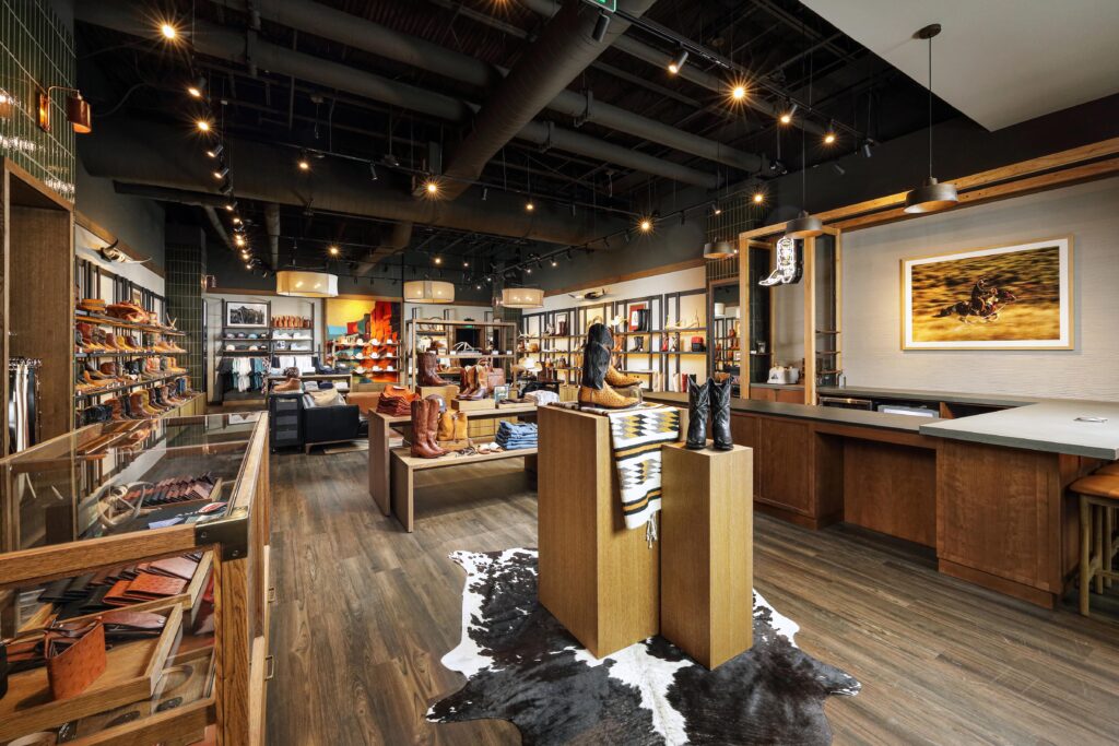 Interior of a Western-style footwear store with wood display pedestals and shelves showcasing various cowboy boots.