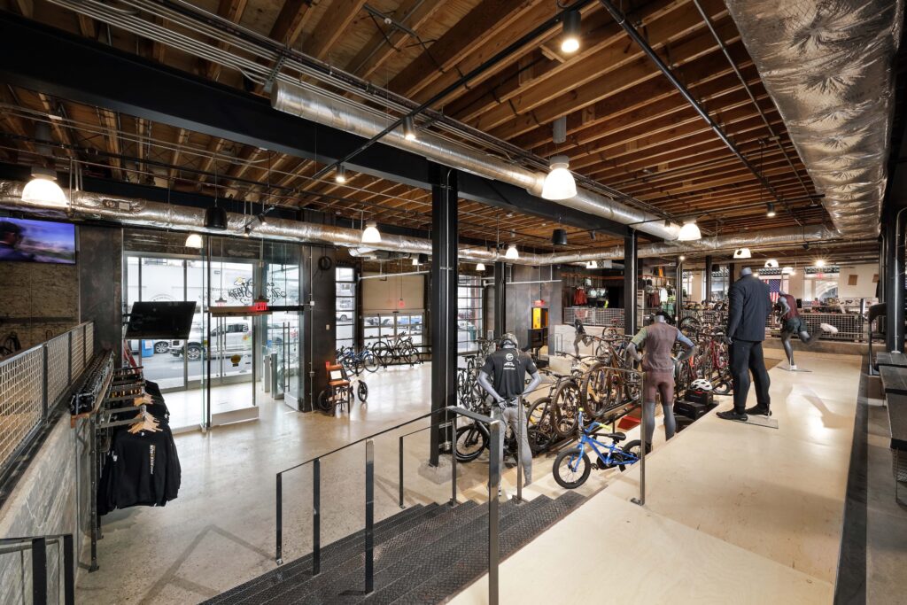 Interior of a spacious bicycle shop with rows of bikes for sale, mannequins, and an open floor plan.