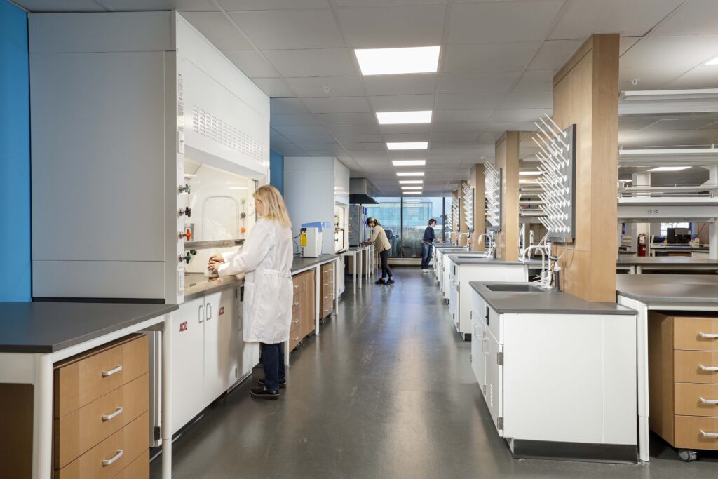Three researchers work at lab benches in a modern laboratory.