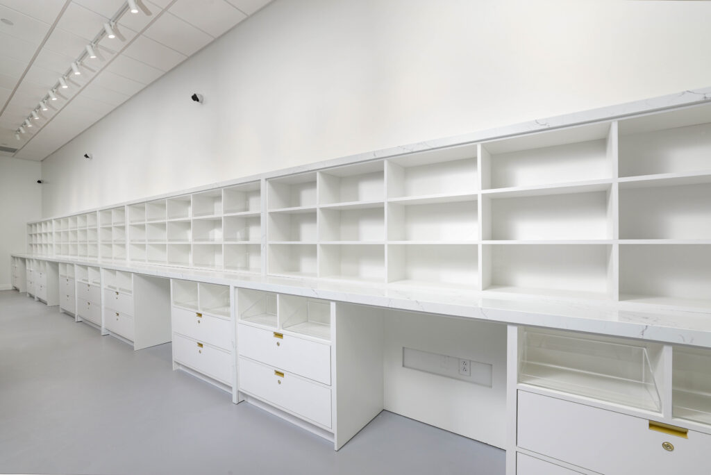A row of white retail shelving units with drawers and white marble-patterned countertops.