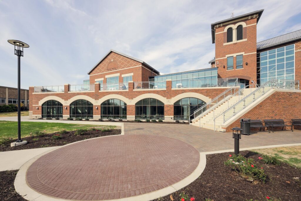 A multi-story brick building with arched windows, a terrace, and an outdoor staircase leading to a second-floor entrance.