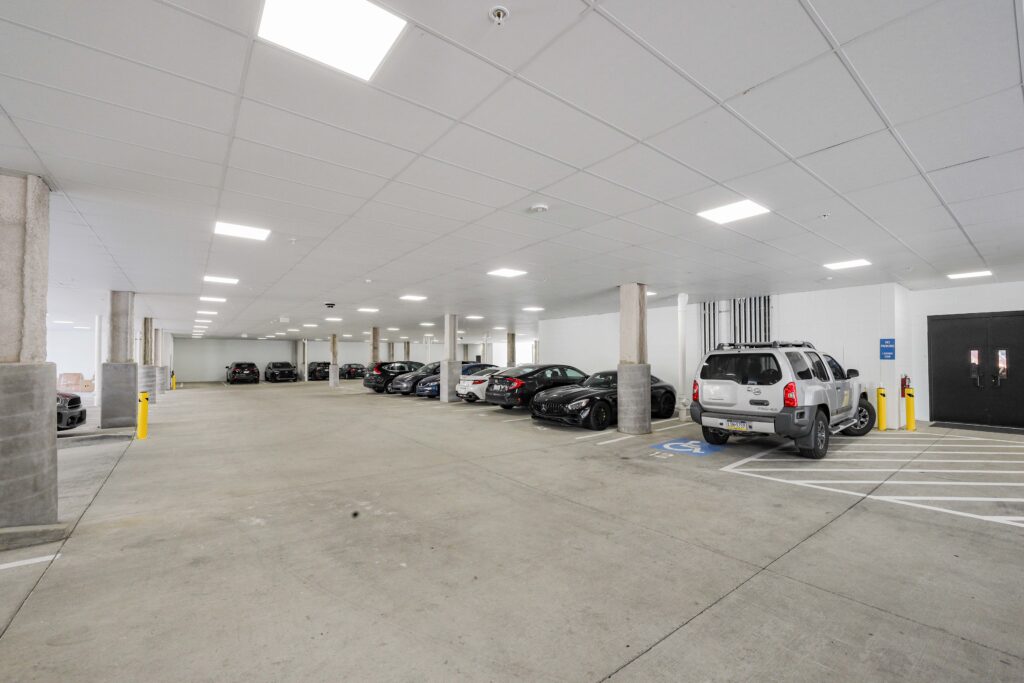 An indoor parking garage with rows of parked cars, including a silver SUV in a designated accessible parking space.